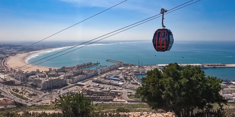 Midway view from Agadir Oufla climb, capturing Agadir's cityscape, Atlantic beach and cable cars
