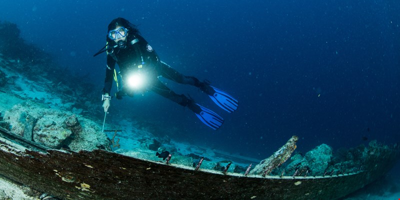scuba diver over the wooden wreck of a diving boat with tanks in