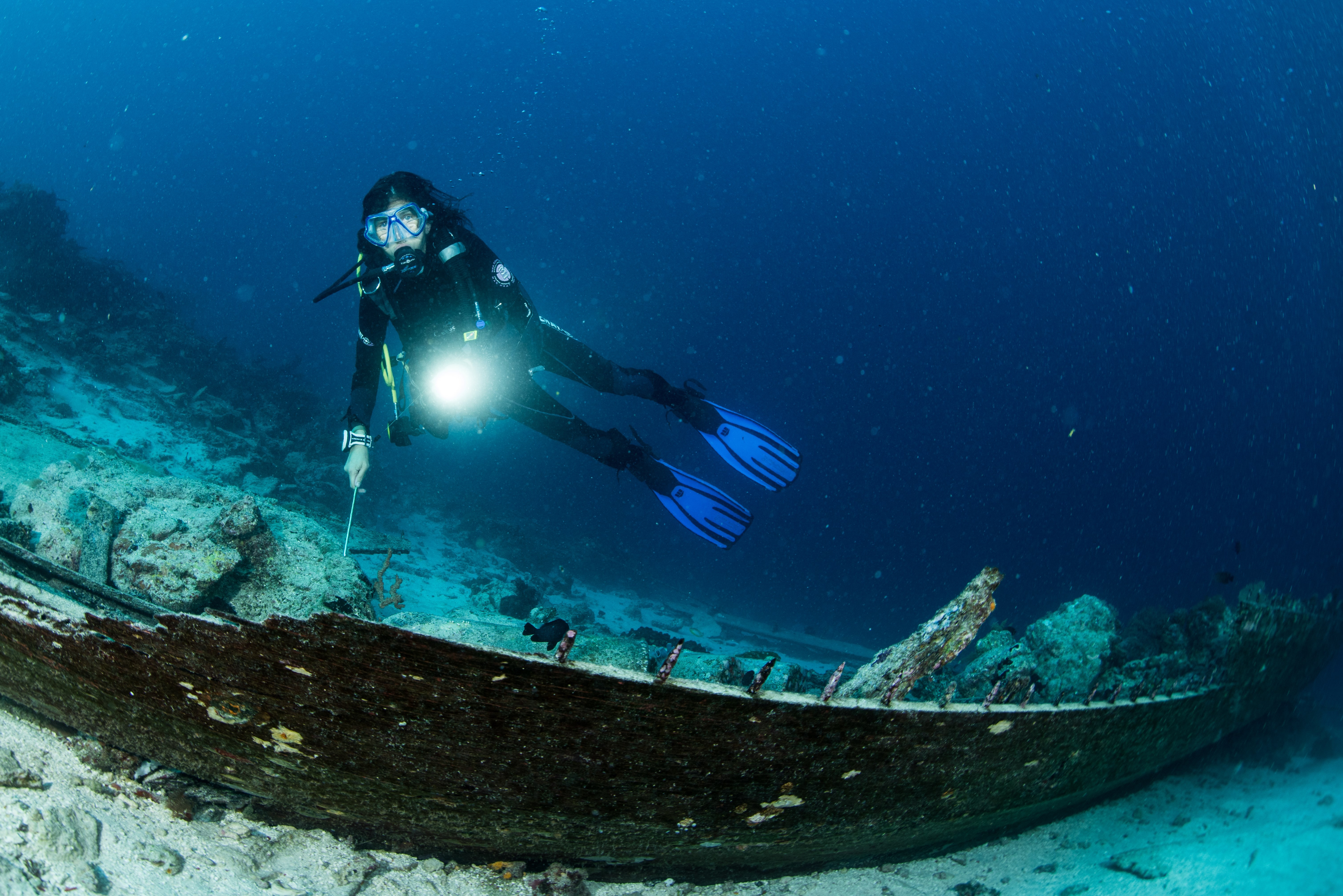 scuba diver over the wooden wreck of a diving boat with tanks in