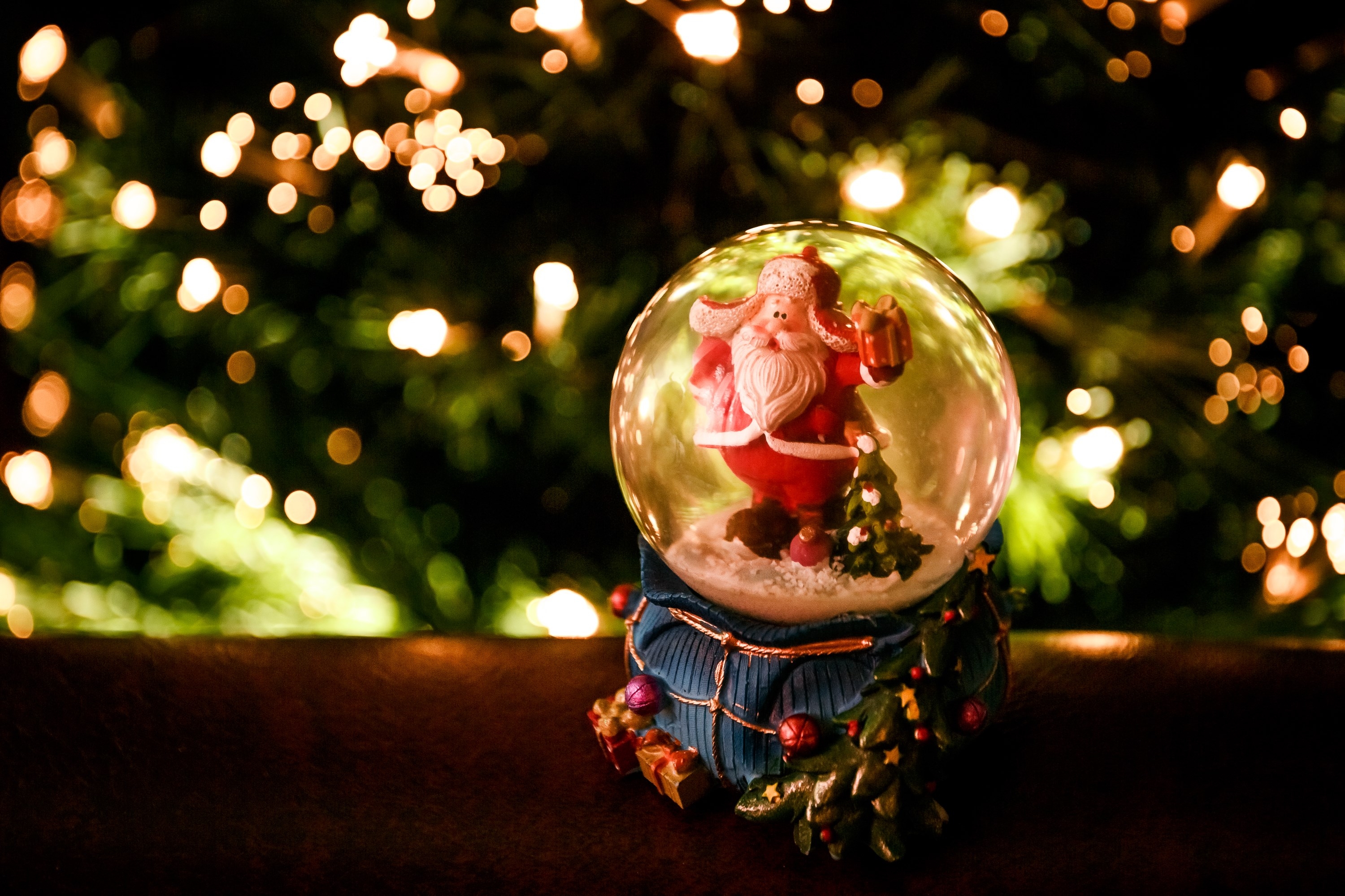 Santa Claus in a glass snowglobe under the tree at the new year time