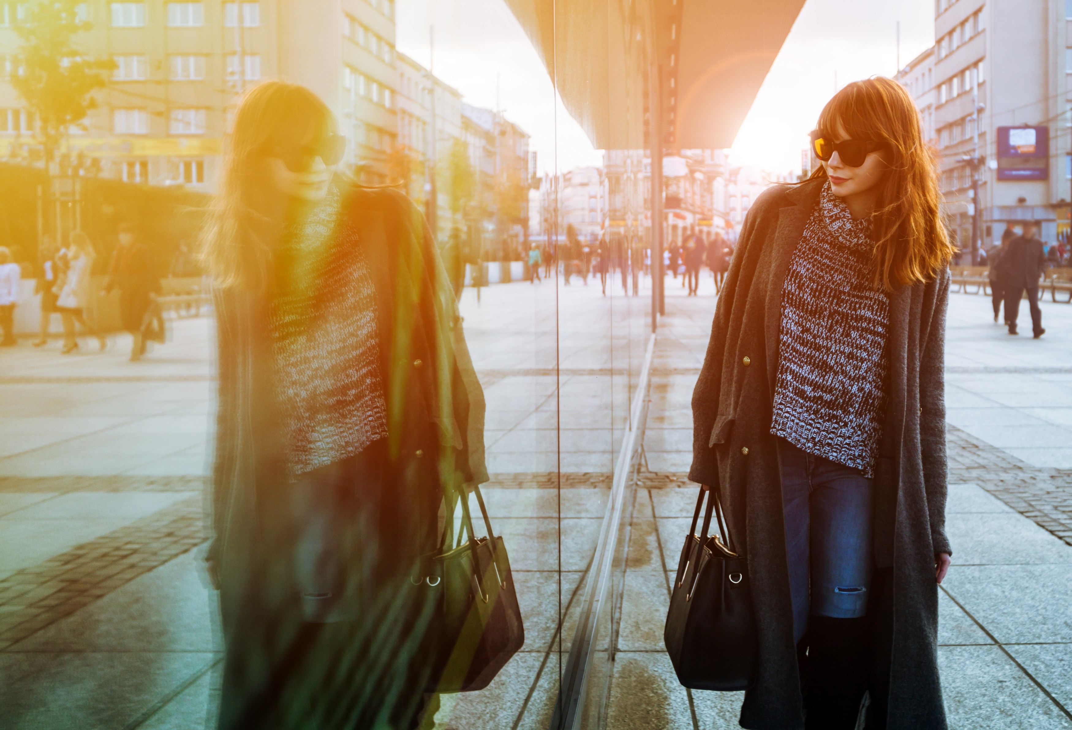 Woman in coat walking on street and looking at shopping window
