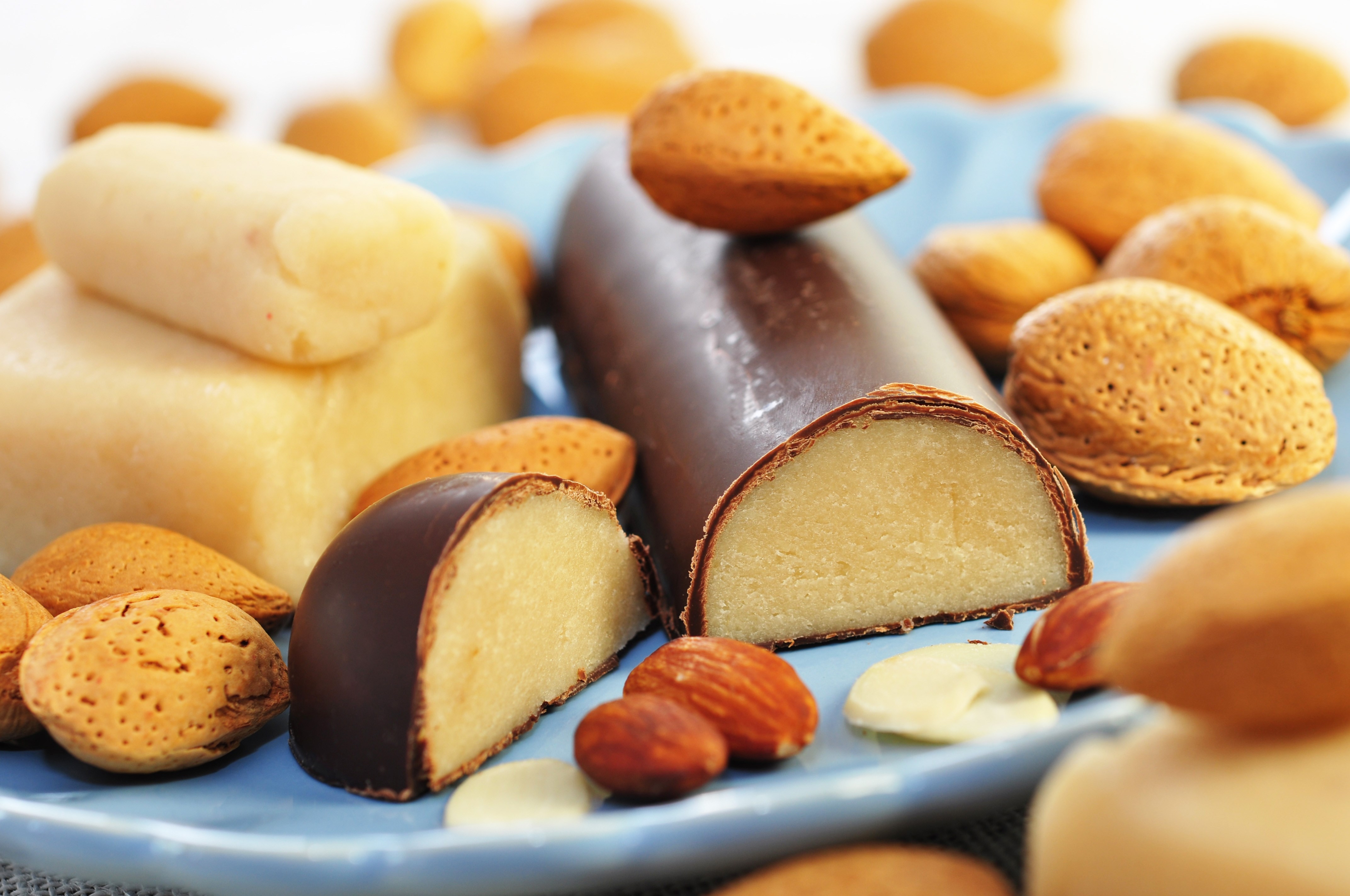 Marzipan and raw almonds on plate, closeup.