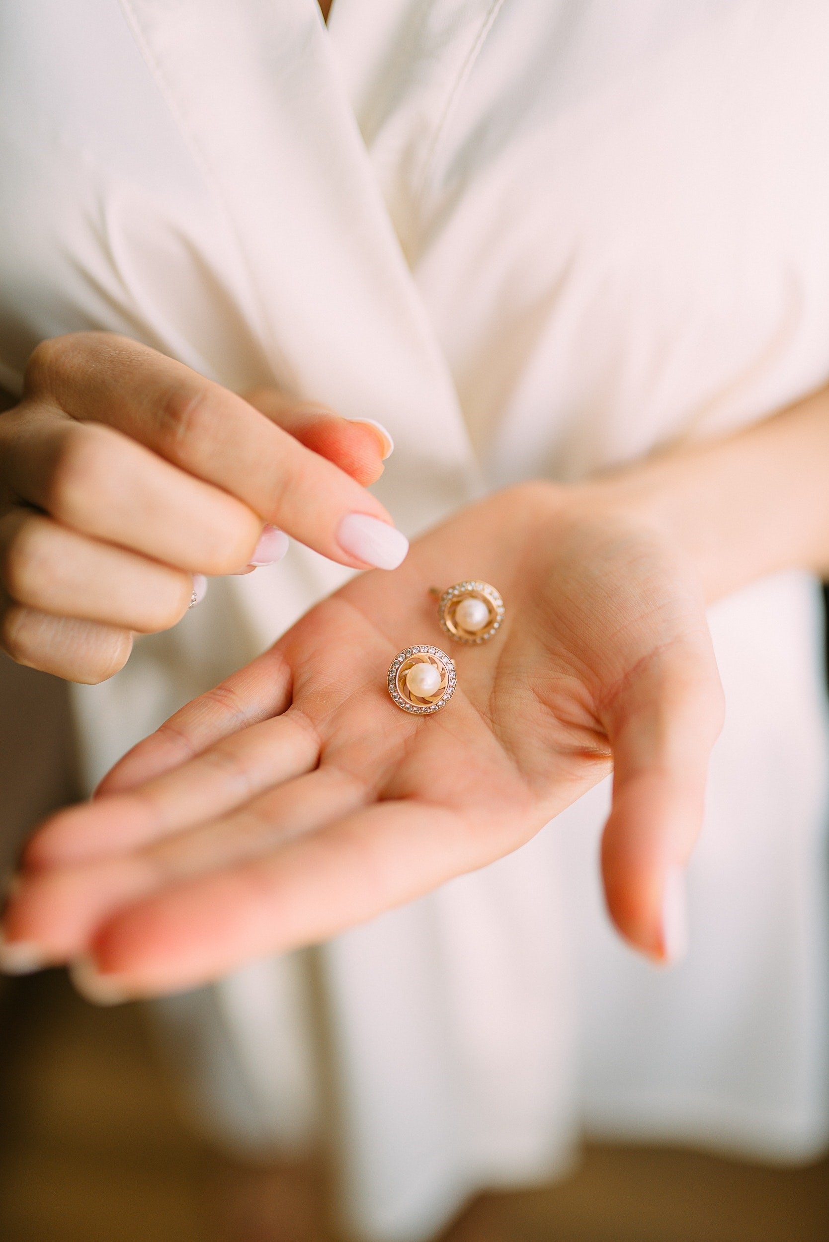 woman holding pearl and gold earrings