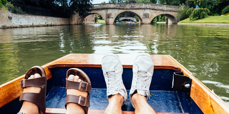 Man and woman feet on a boat punting in the river in Cambridge. Focus on feet.