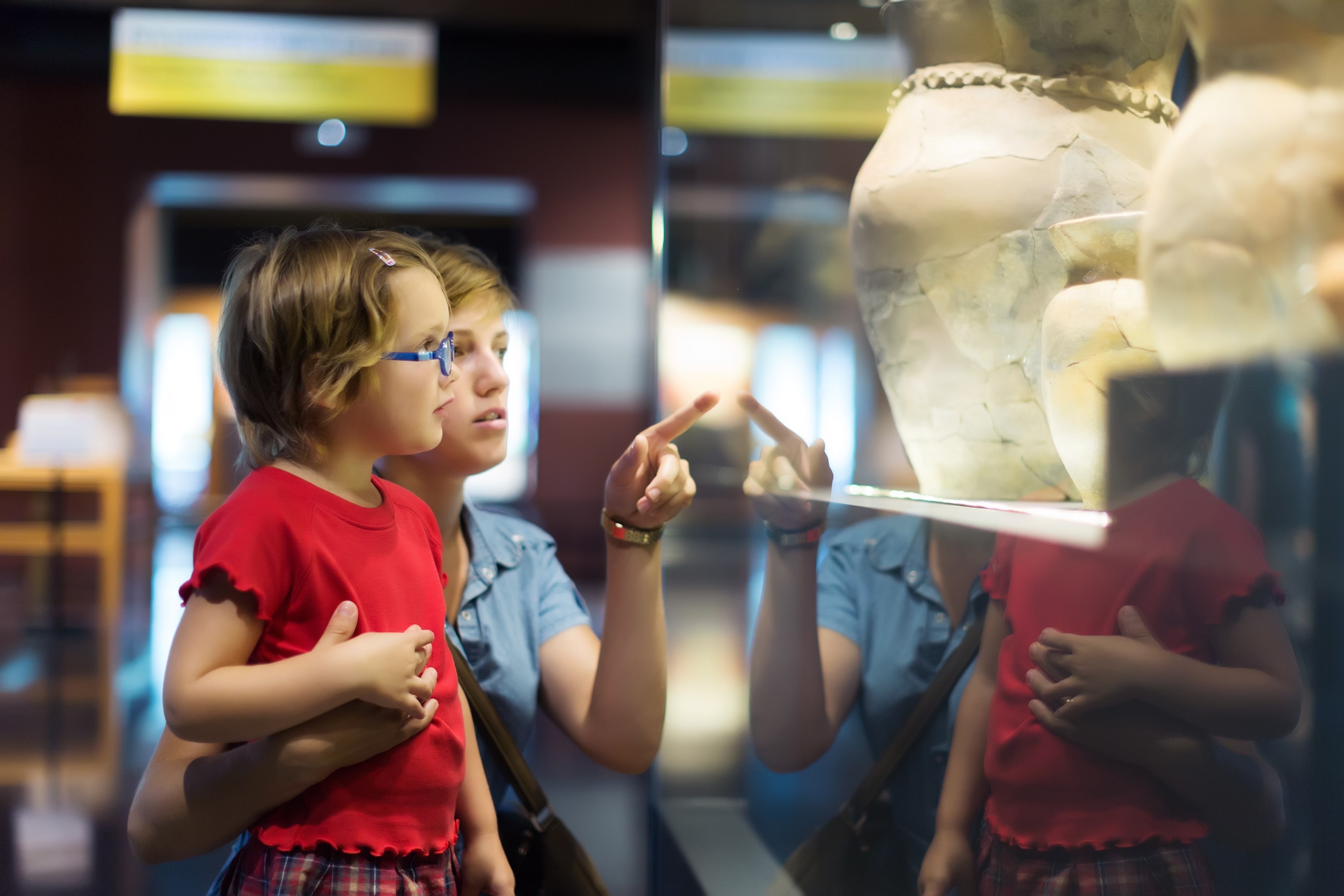 Woman and child looking old ancient amphora in historical museum
