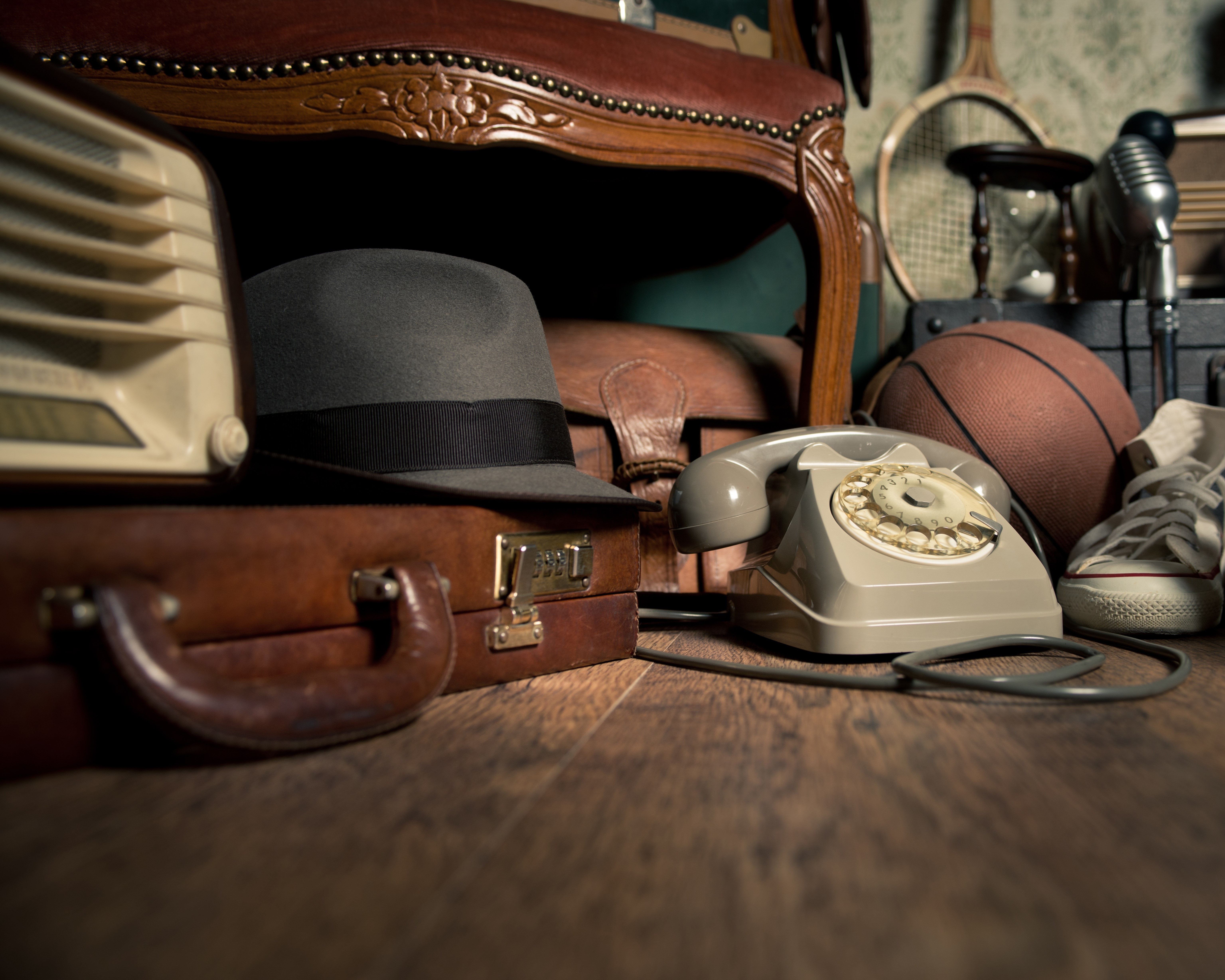 Group of vintage objects on attic hardwood floor, including old toys, phone and sports items.
