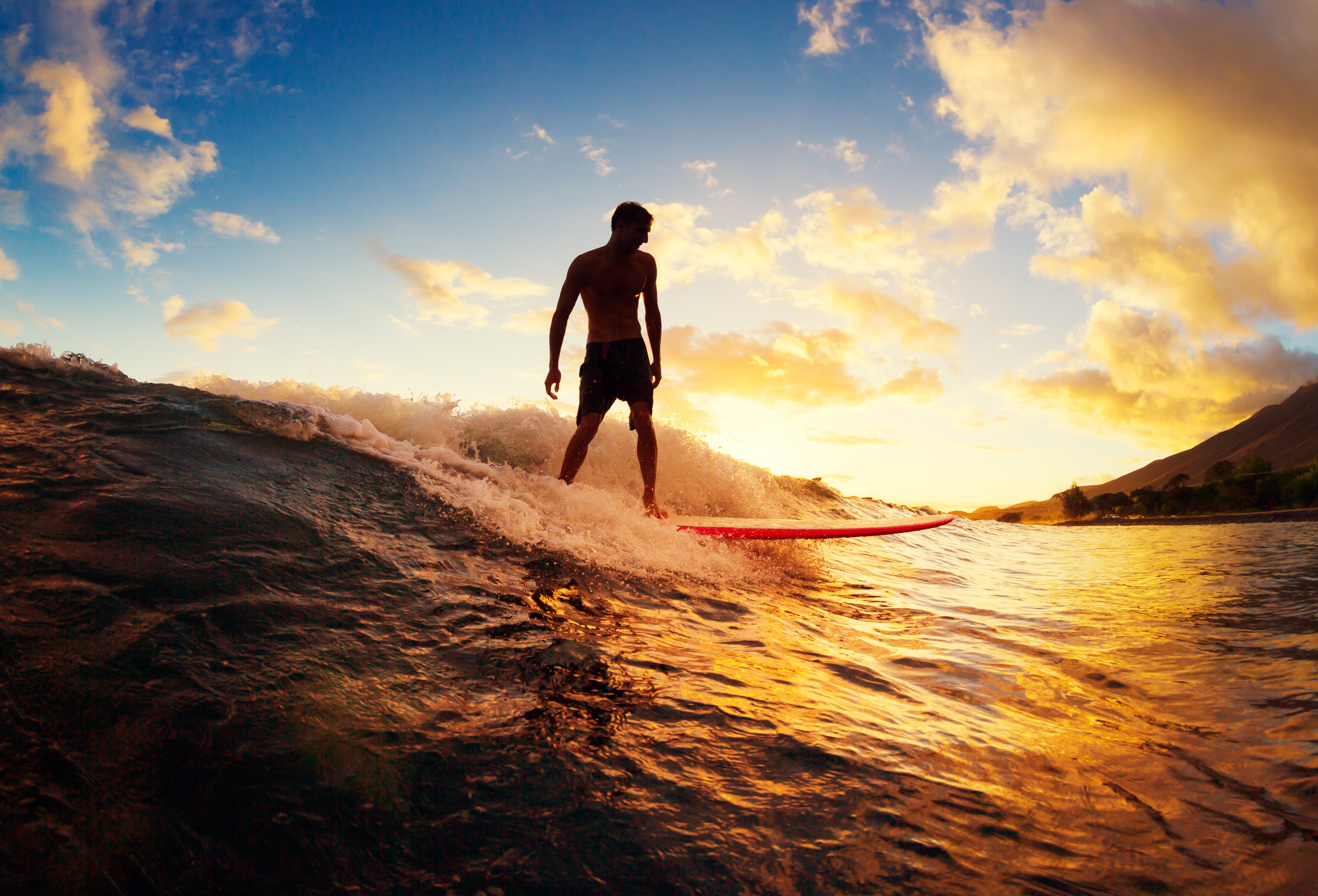 Young Man Riding Wave at Sunset