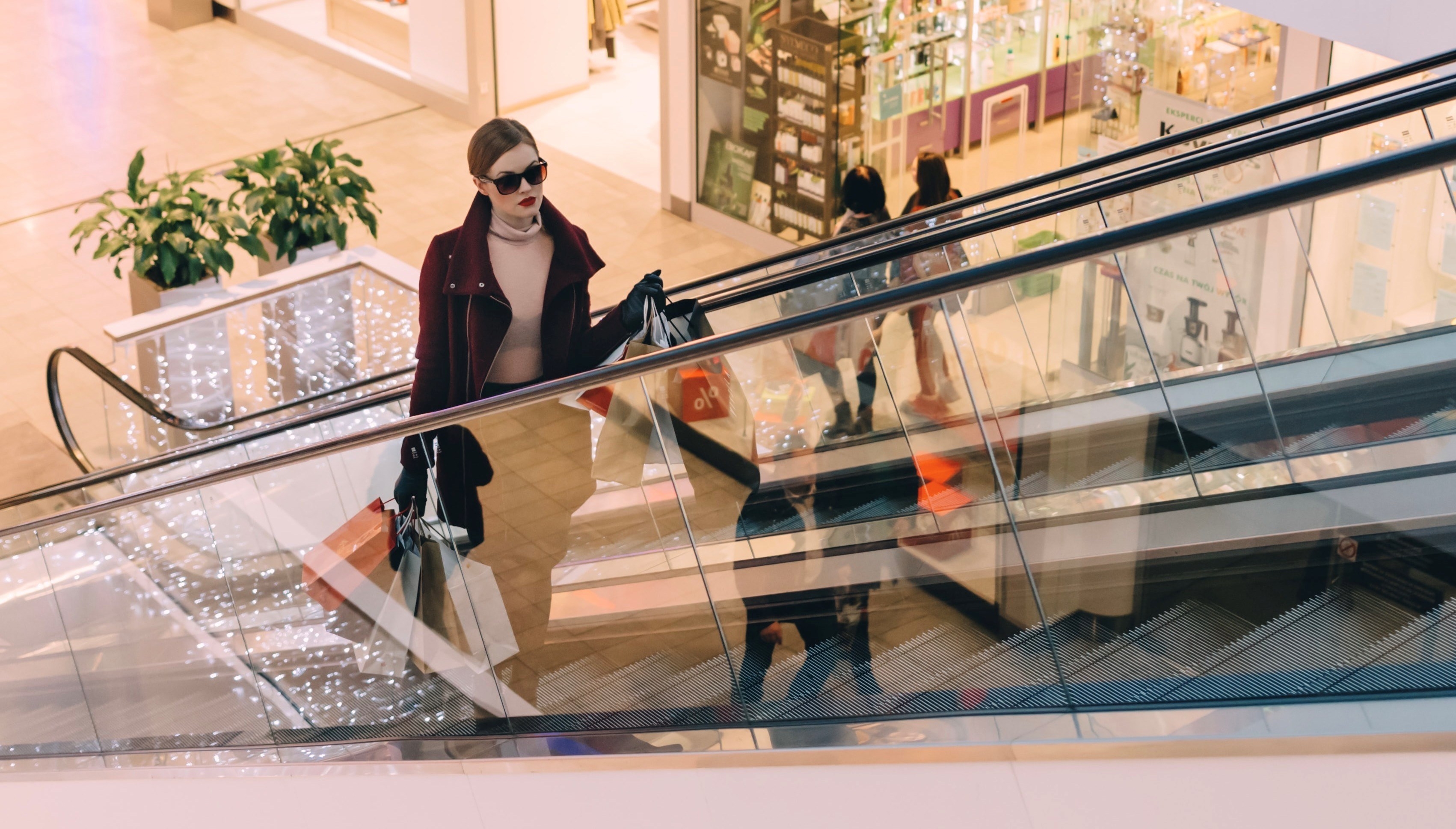woman with shopping bags on an escalator