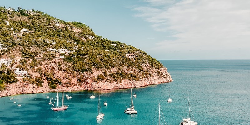 Blue sea and sailboats at the Sant Joan de Labritja Beach on Ibiza