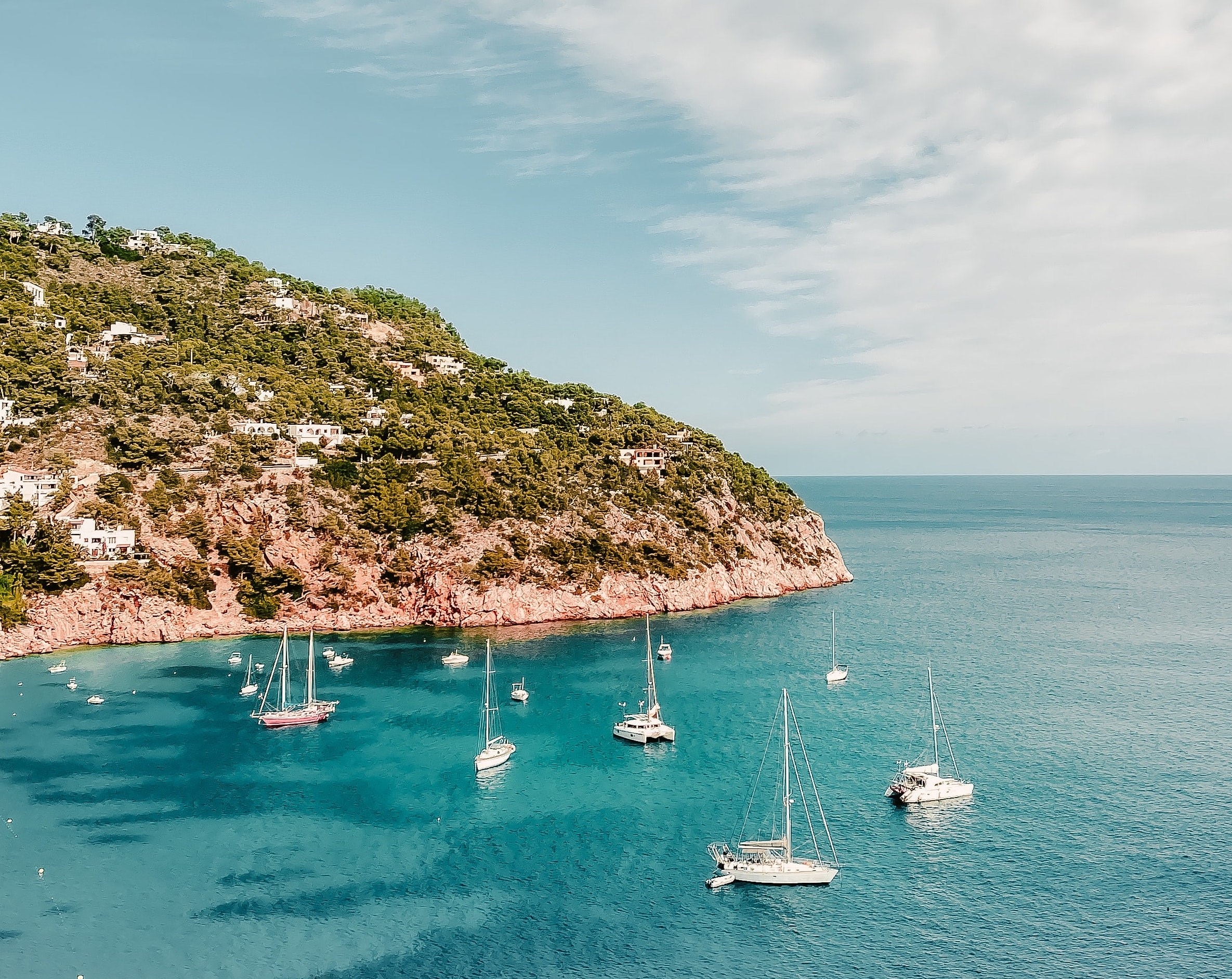 Blue sea and sailboats at the Sant Joan de Labritja Beach on Ibiza