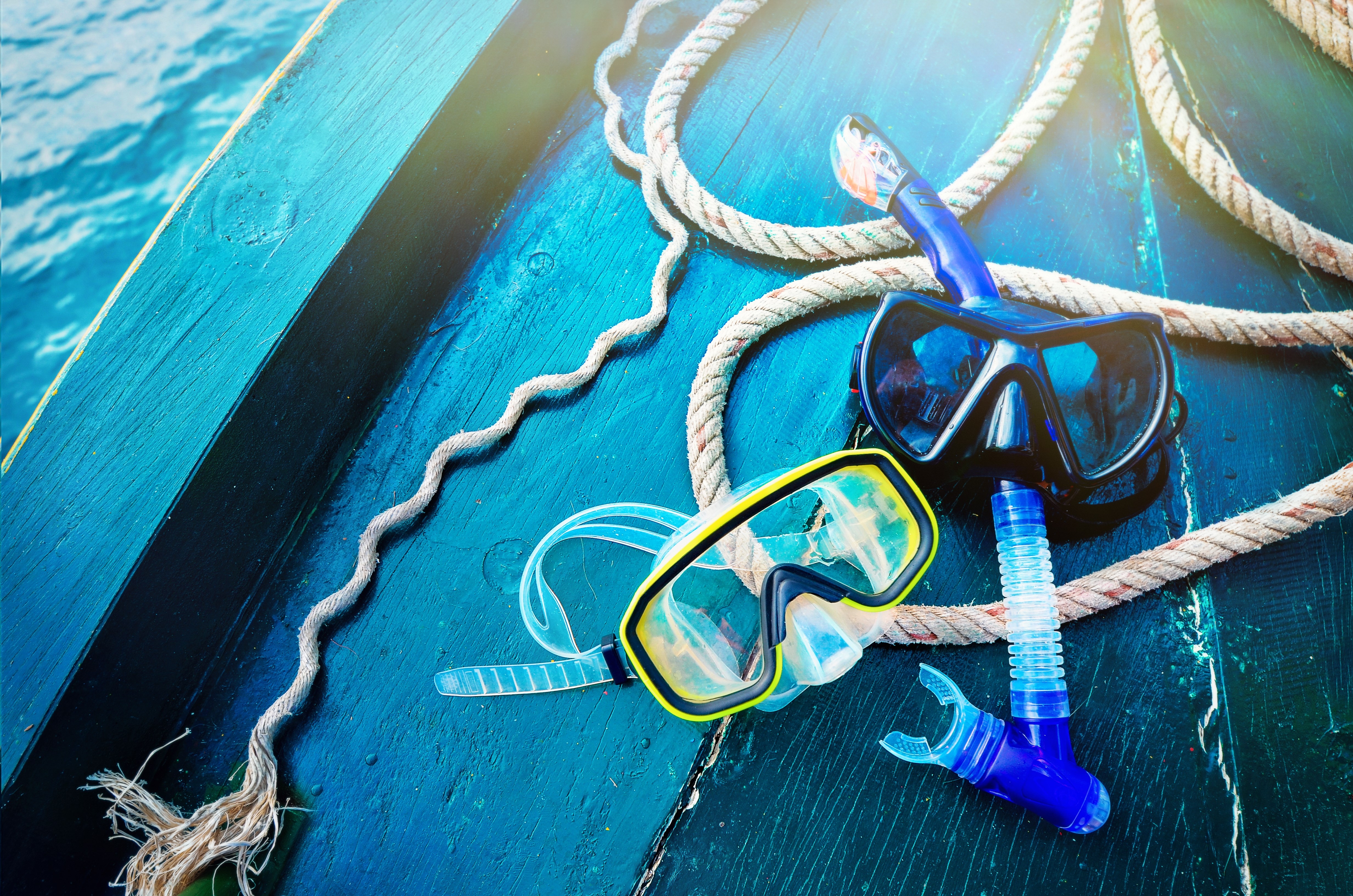 Scuba diving and snorkeling. Two snorkel on blue wood background. The deck and the nose of the ship with a solar glare