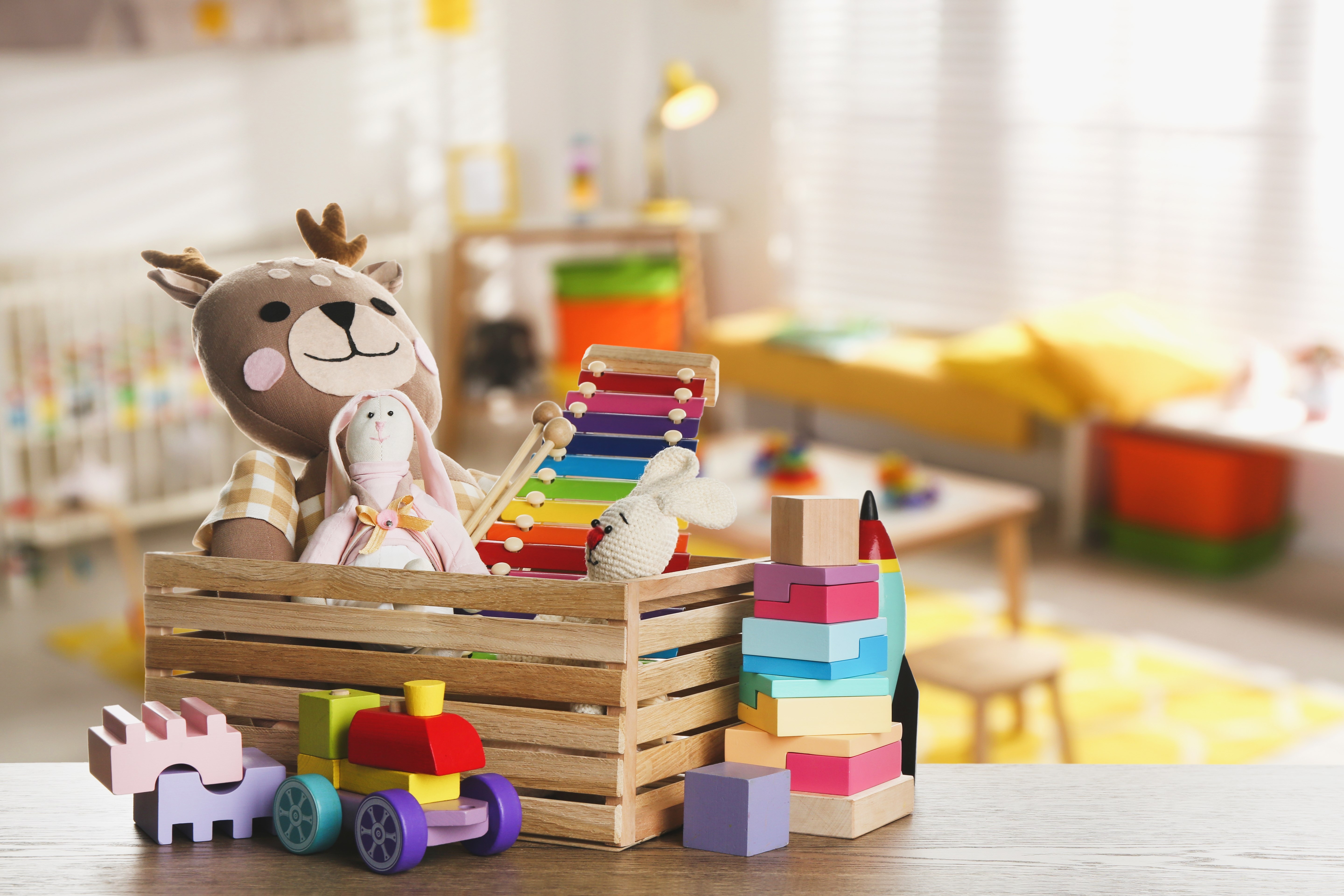 Set of different cute toys on wooden table in children's room