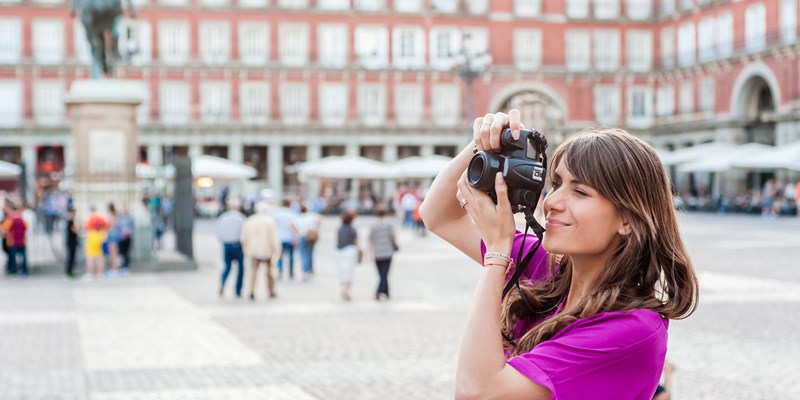 Young woman a photo camera and taking picture in Plaza Mayor square, Madrid