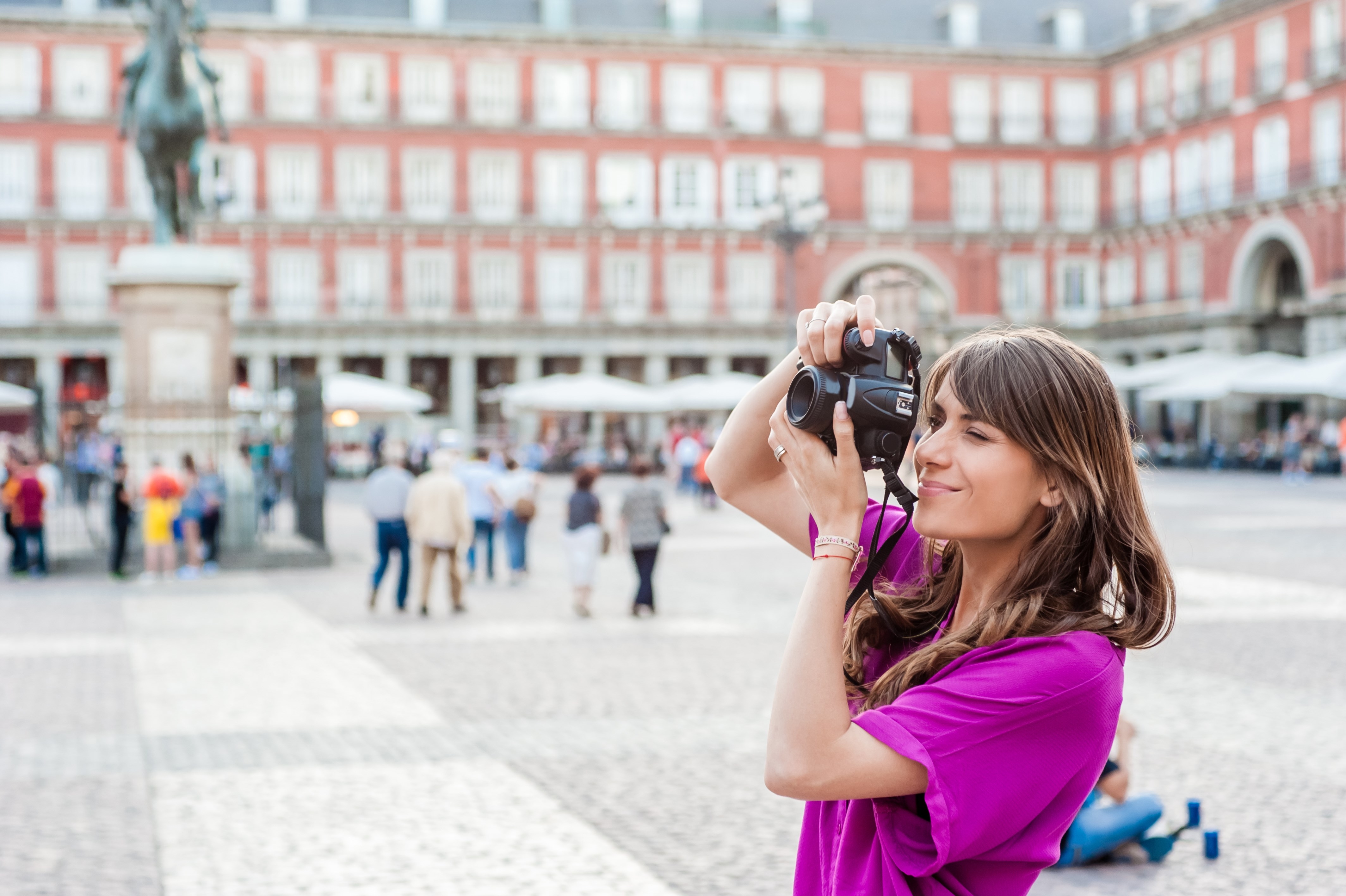 Young woman a photo camera and taking picture in Plaza Mayor square, Madrid
