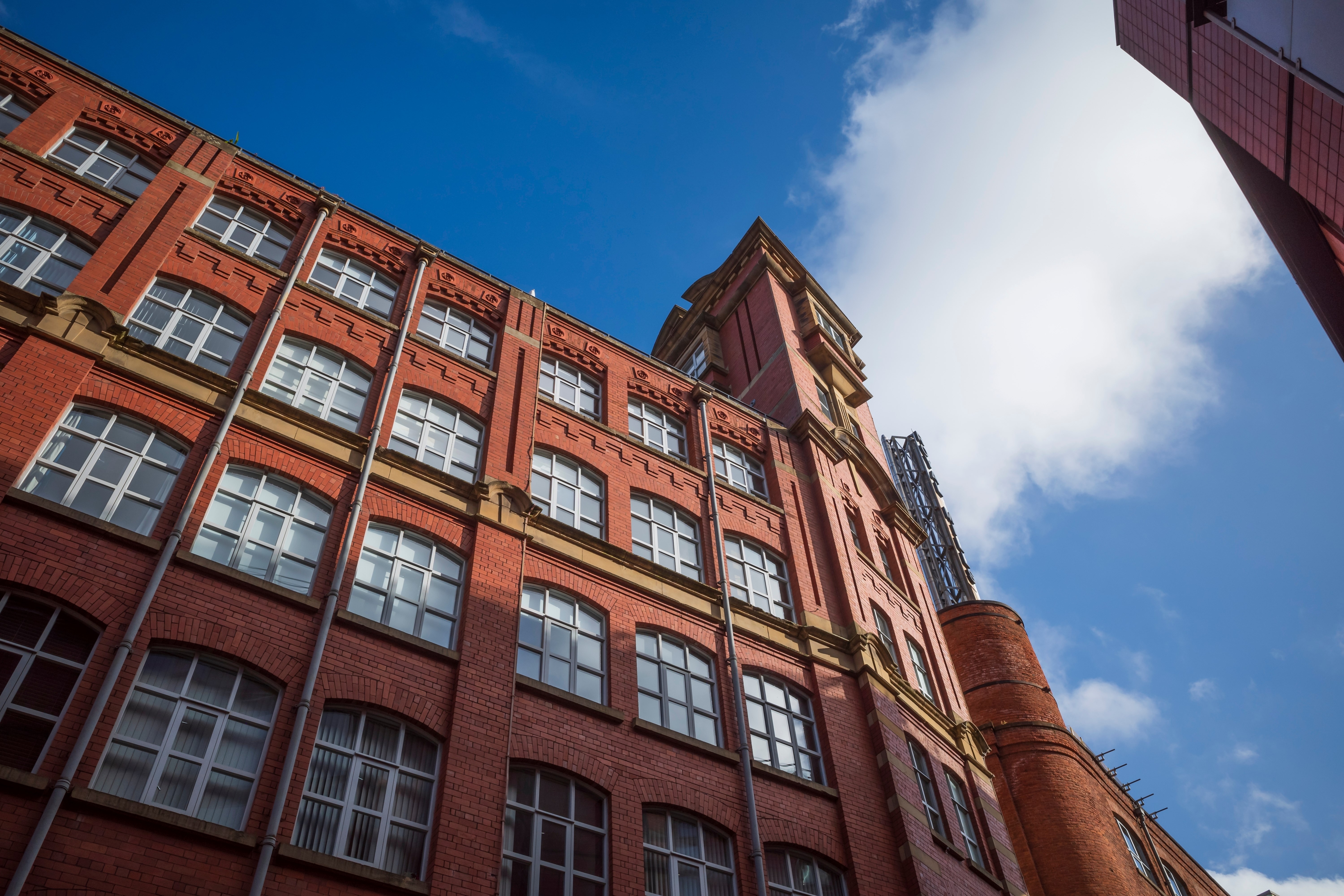 Manchester city center. Historic red brick building under a clear blue sky and fluffy clouds