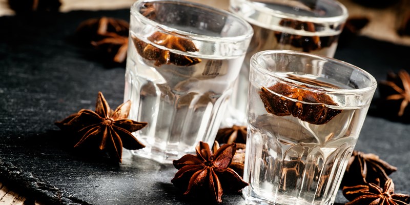 Homemade anise liqueur in a glass on a dark background