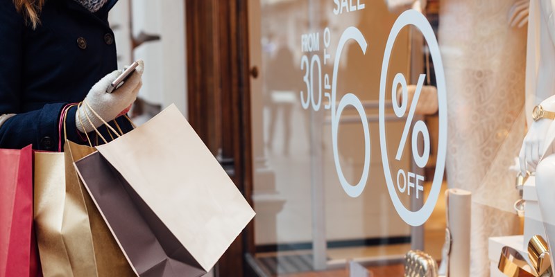 Closeup of woman with shopping bags in front on store window