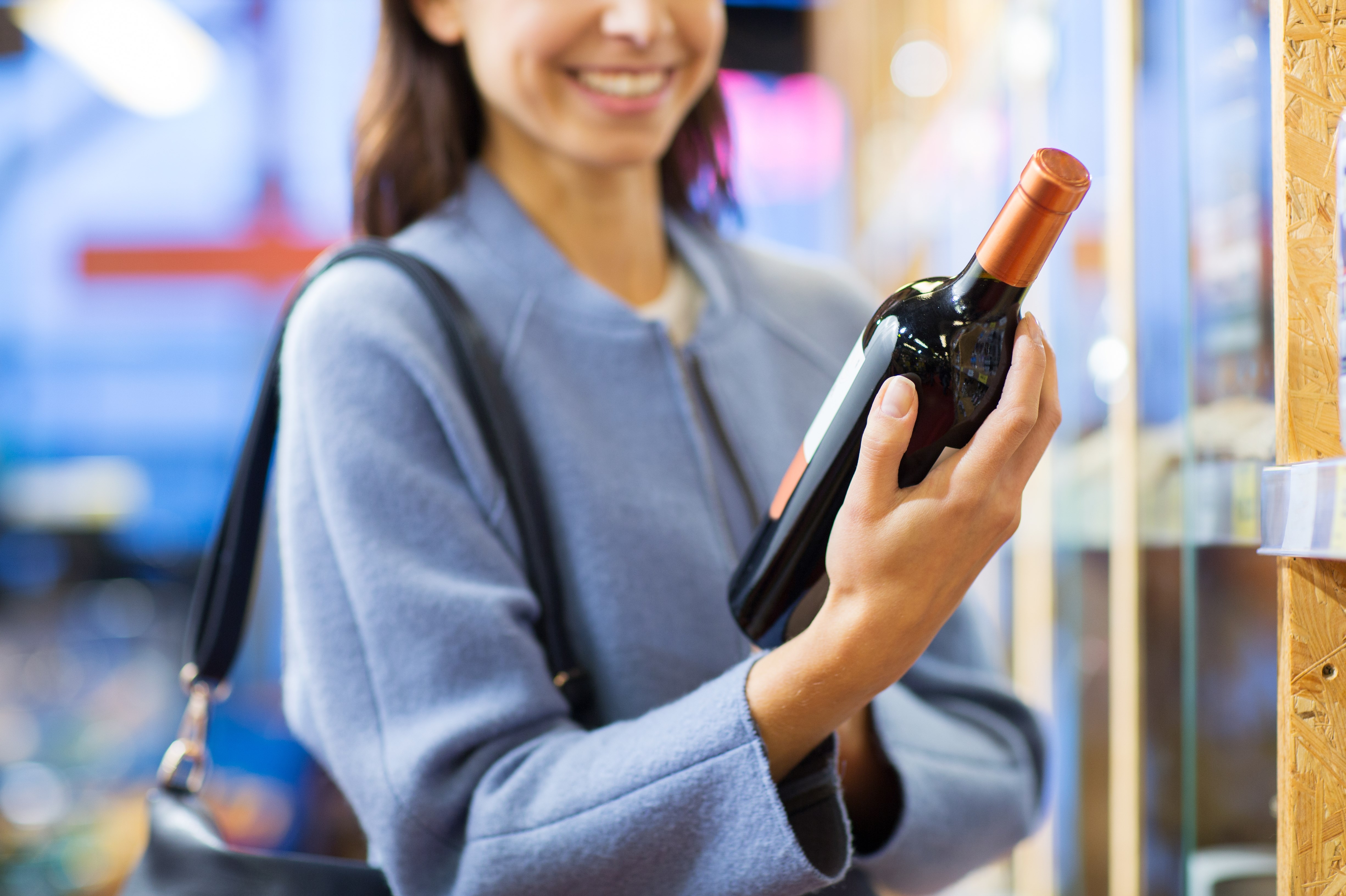happy young woman choosing and buying wine