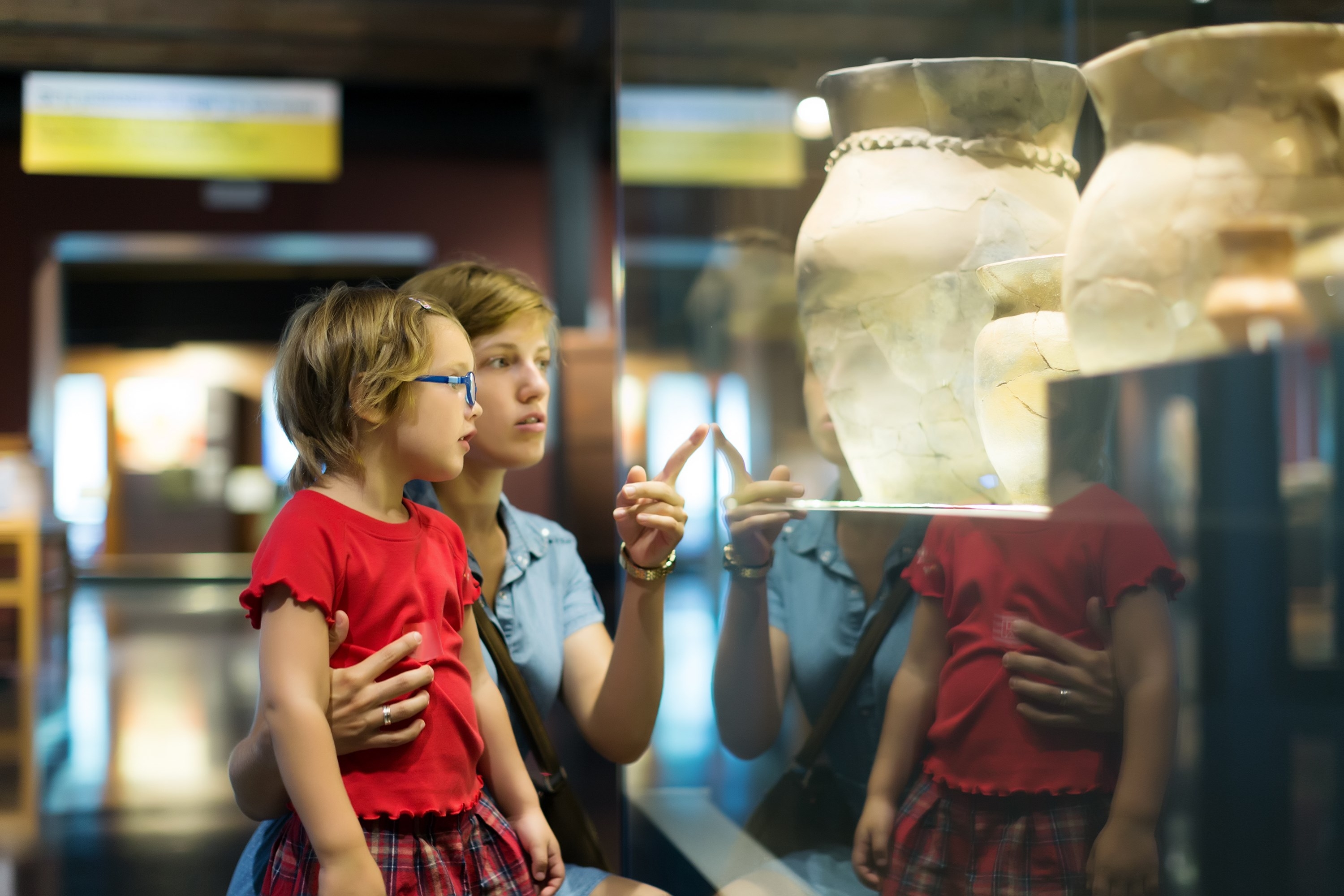 Woman and child looking old ancient amphora in historical museum