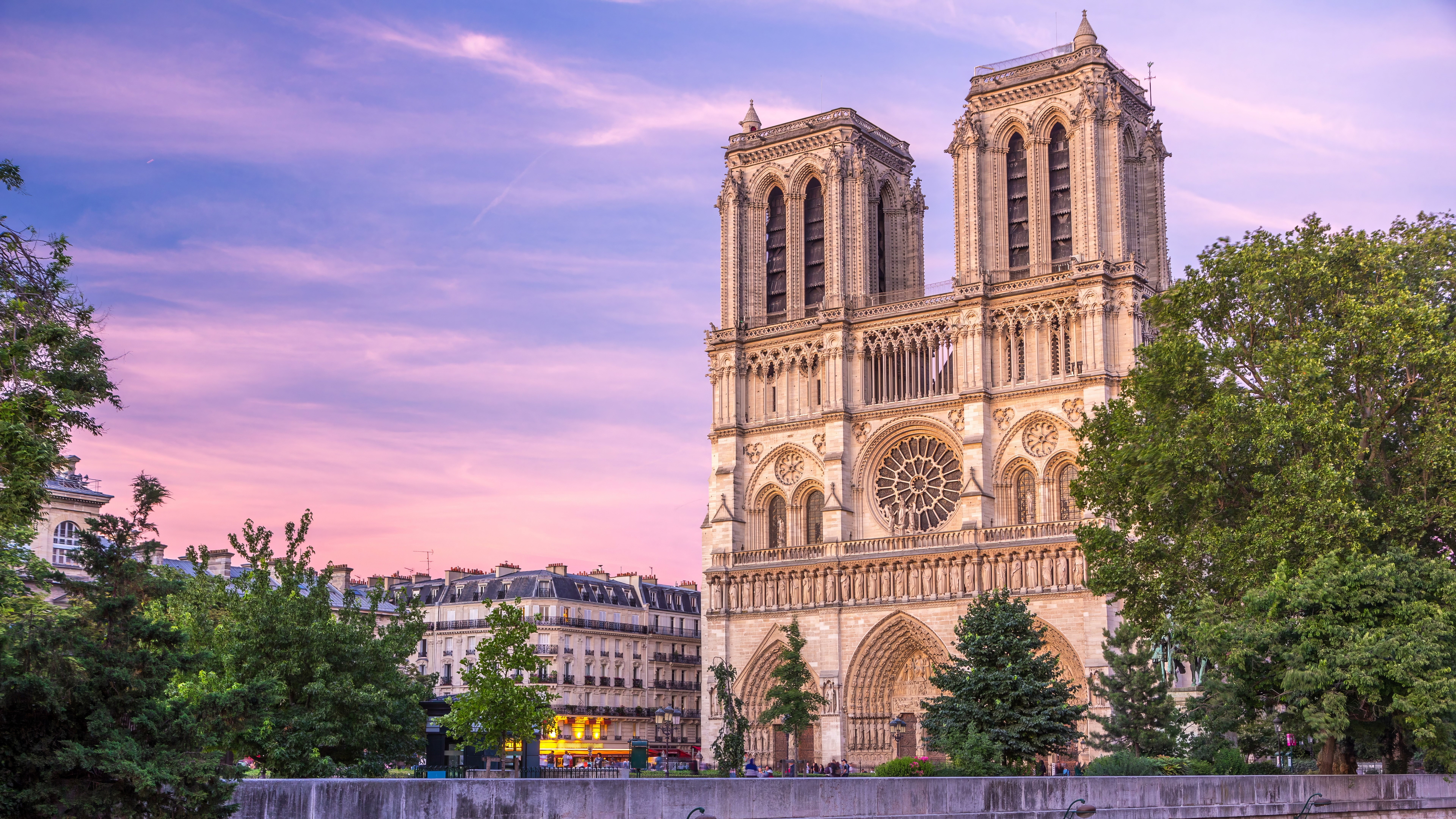 Front view of illuminated Notre Dame De Paris cathedral day to night transition timelapse after sunset. Colorful sky on a background. Paris, France, Europe. View from Cardinal Lustiger bridge.