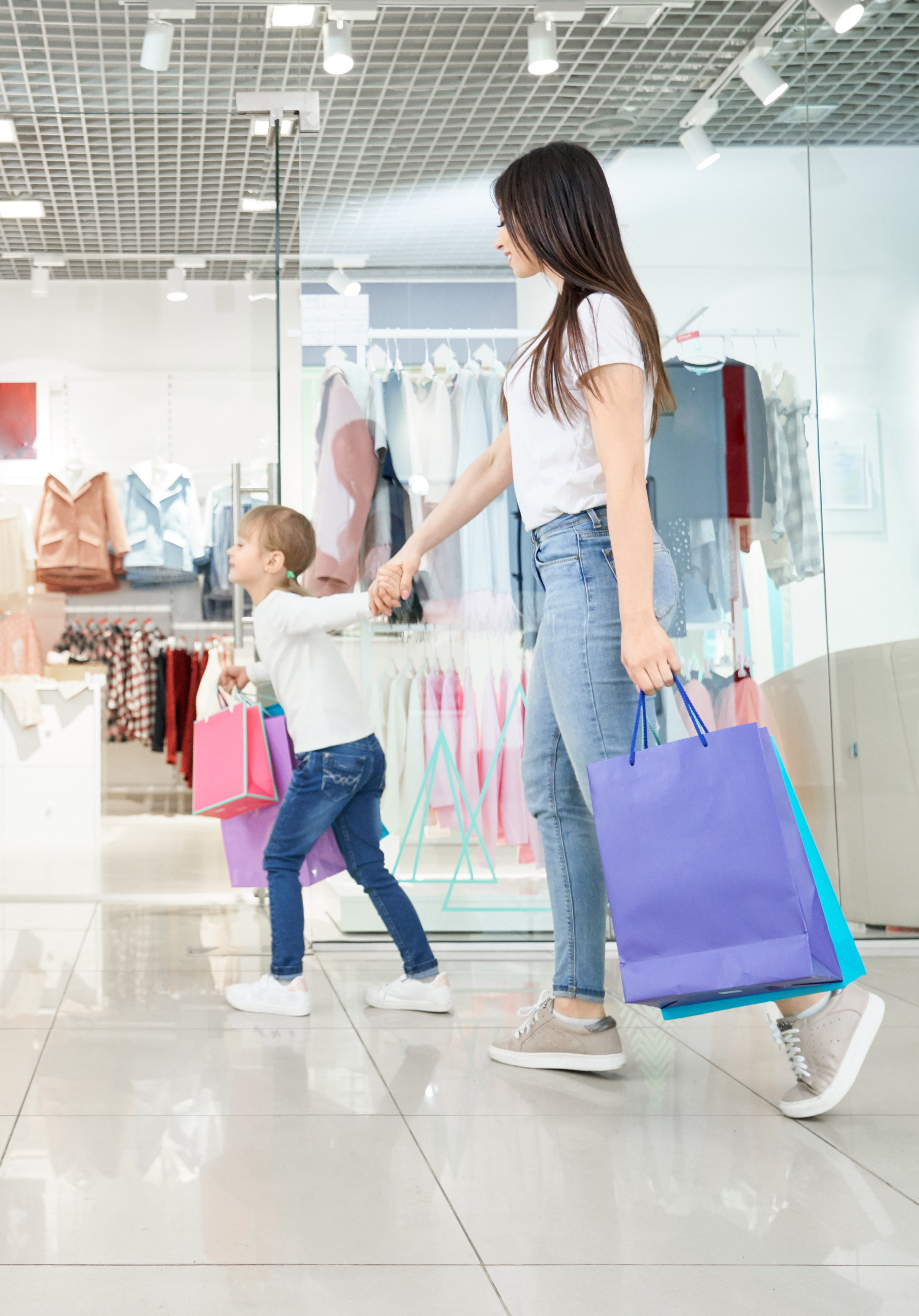 Positive girl keeping hand of woman and running in shops
