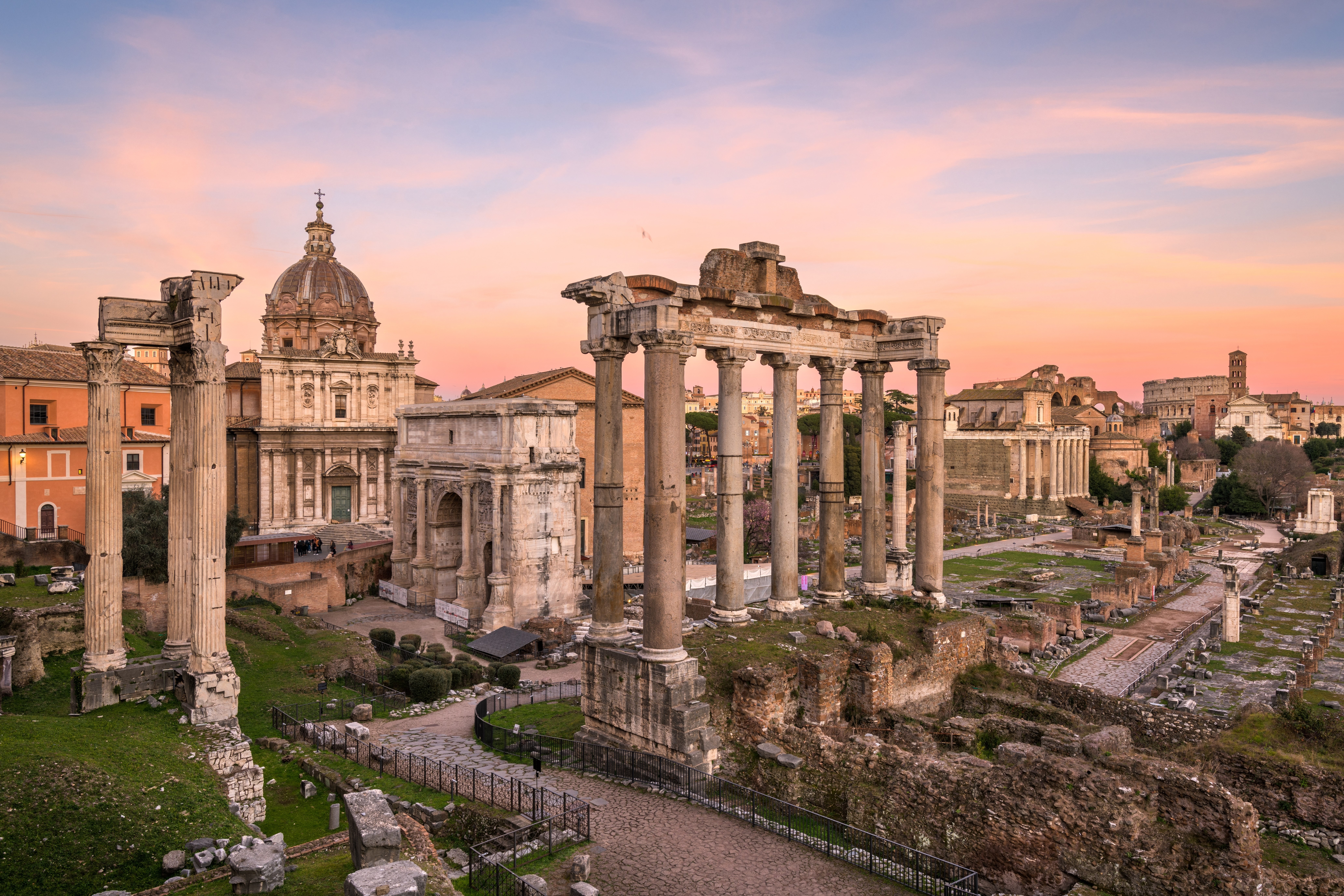 Rome, Italy at the historic Roman Forum ruins at dusk.