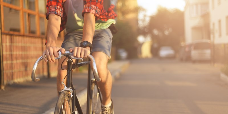 Close up hipster on bike in the city at sunset. Shot with sunflare and without face.