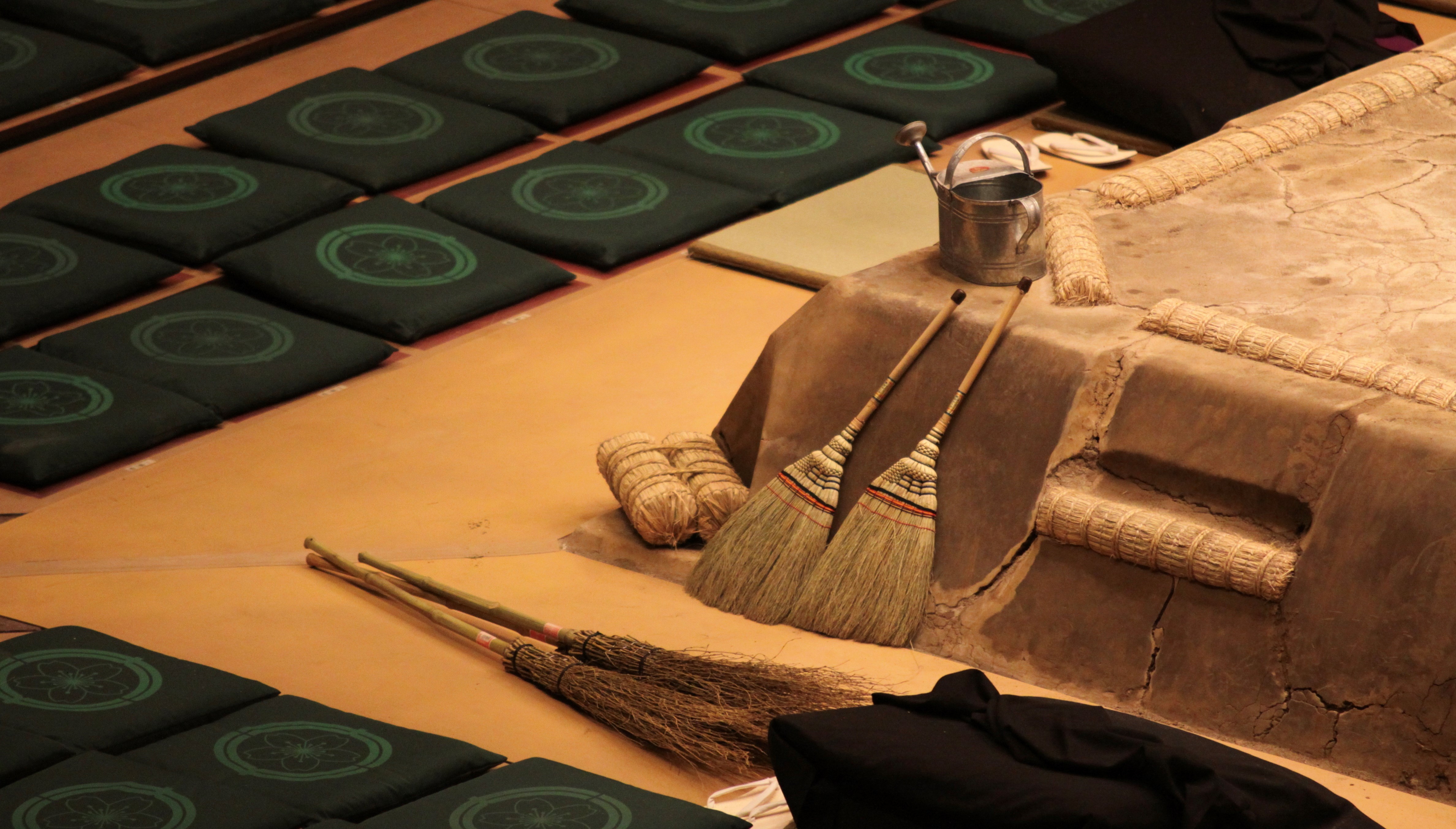 Empty sitting pillows and brooms as equipment next to a fighting ring in a sumo arena in Tokyo, Japan