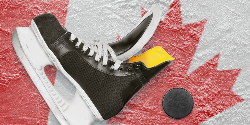 Puck, skates and the image of the Canadian flag on the ice