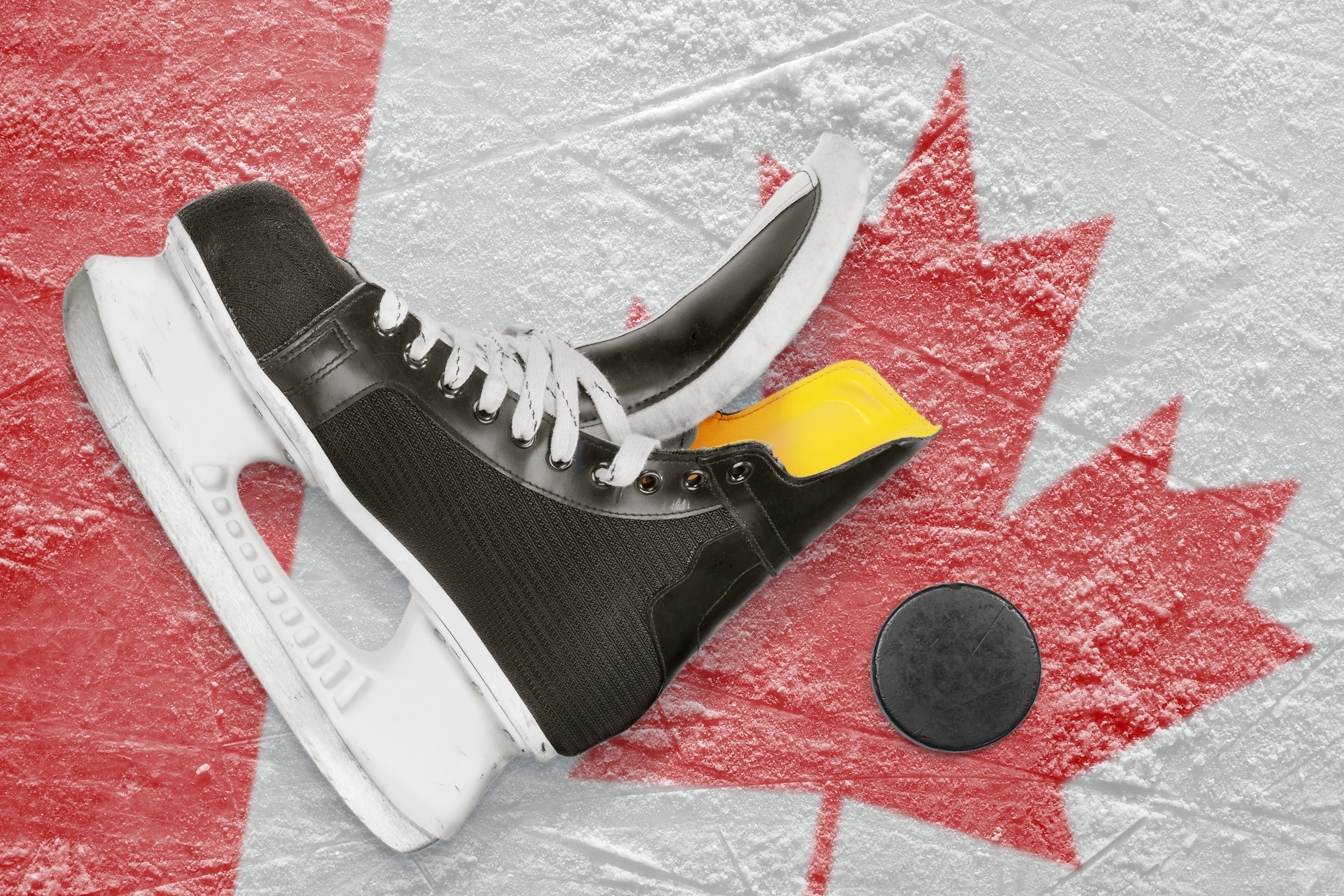 Puck, skates and the image of the Canadian flag on the ice