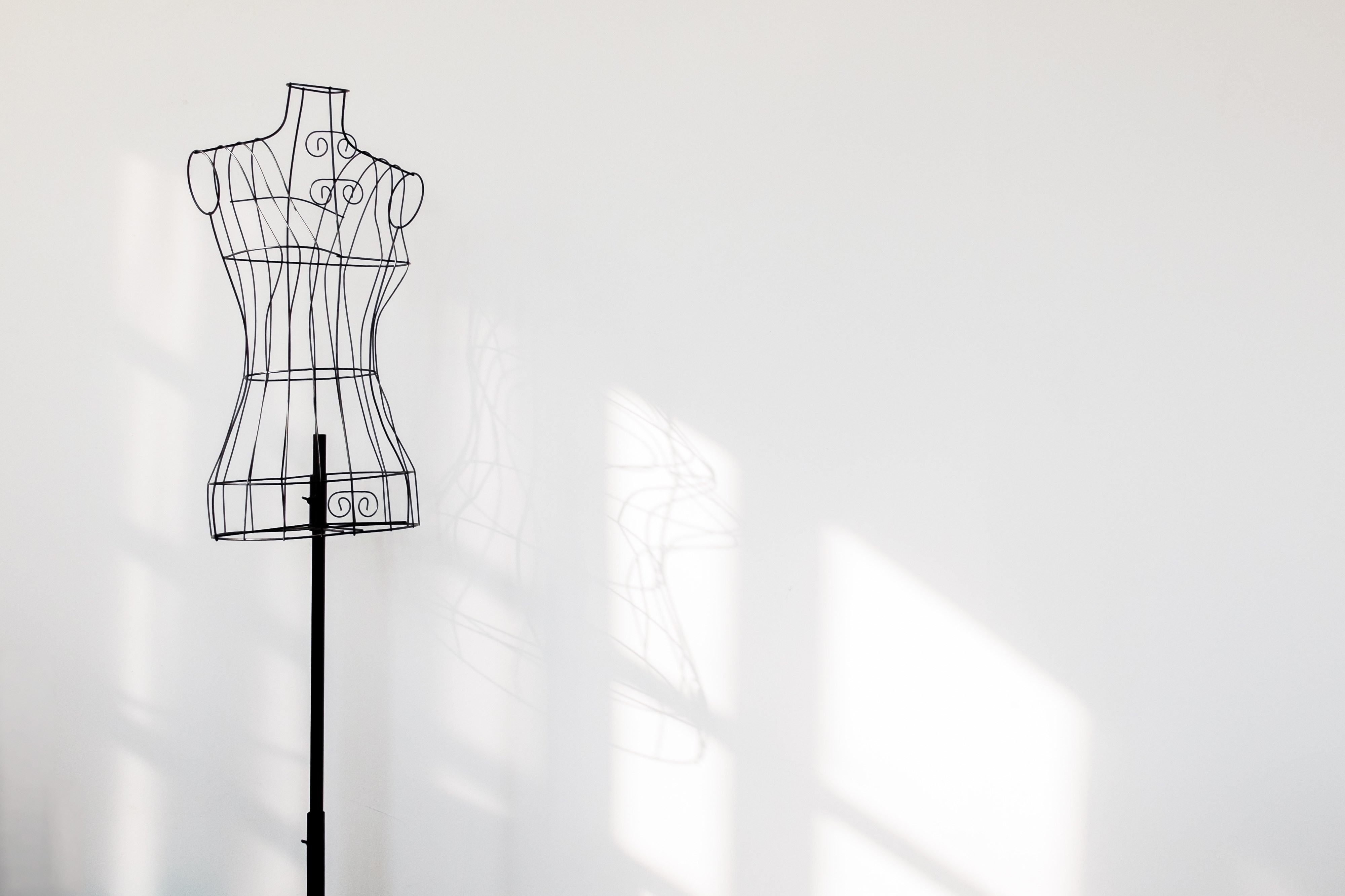 Vintage mannequin stand at white wall.
