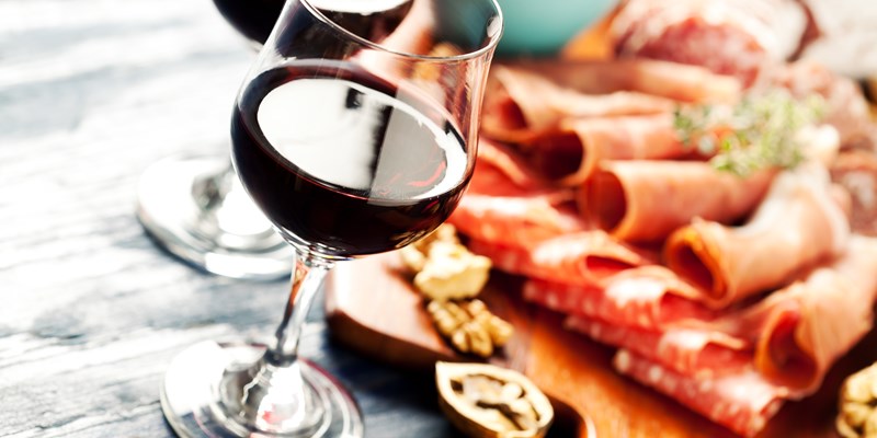 Red wine with charcuterie assortment on the background