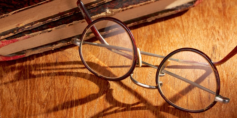Long shadow from vintage eyewear over a wooden table