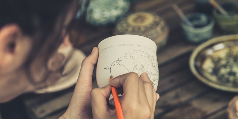 woman painting on a piece of pottery