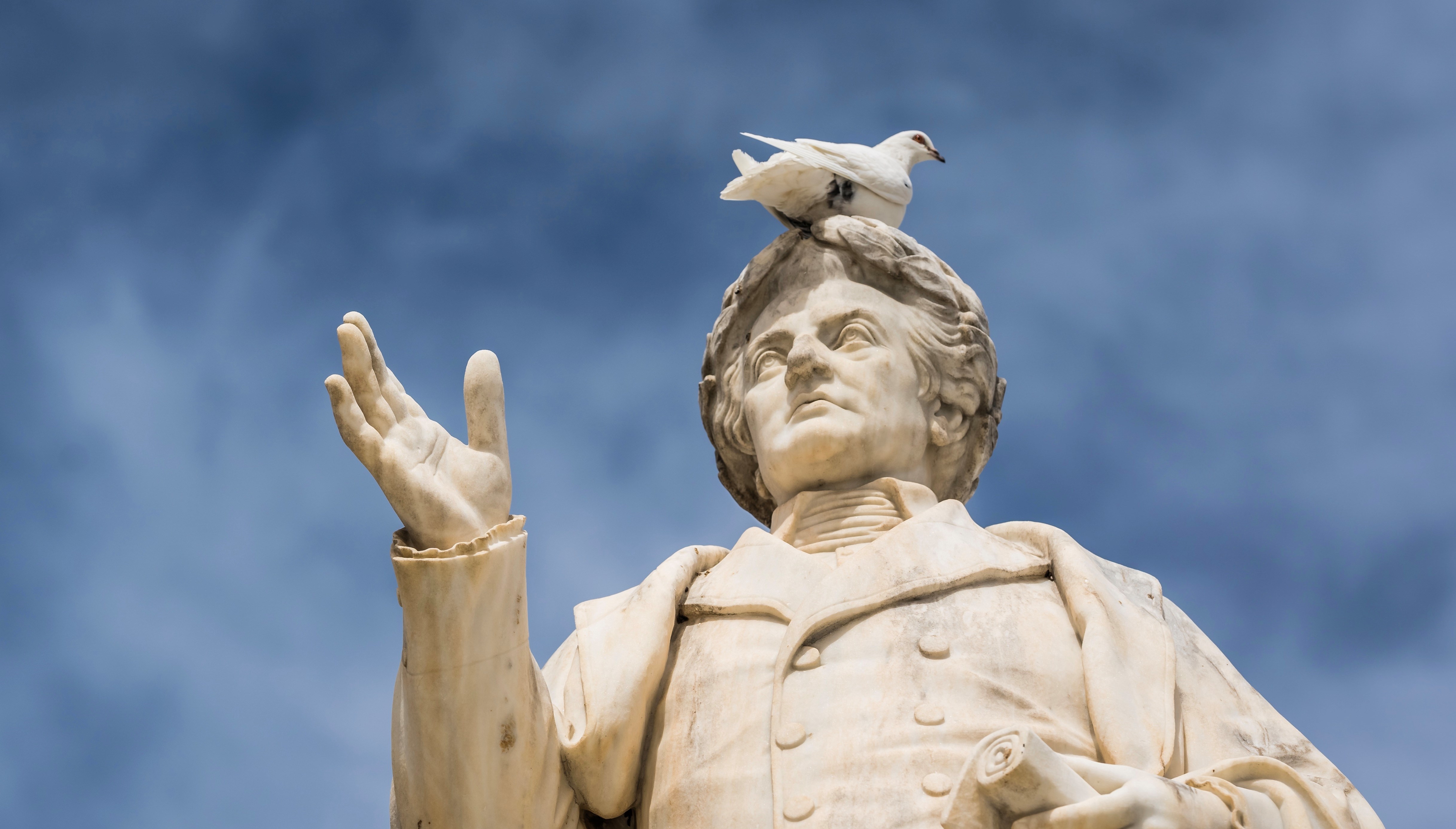 White bird sitting on top of ancient statue of Dionysios Solomos in Zakythos Town square