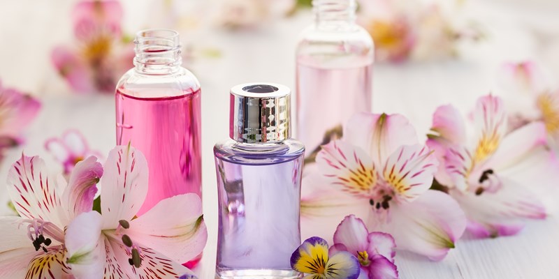 Bottles of essential aromatic oils surrounded by fresh flower
