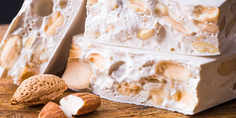 Torrone or nougat with nuts on wood background.