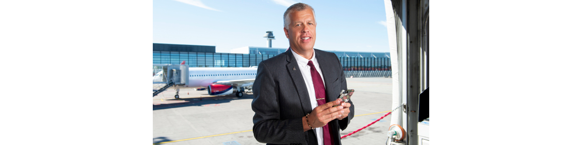 En man i kostym med Arlanda flygtorn i bakgrunden En man i kostym med Arlanda flygtorn i bakgrunden