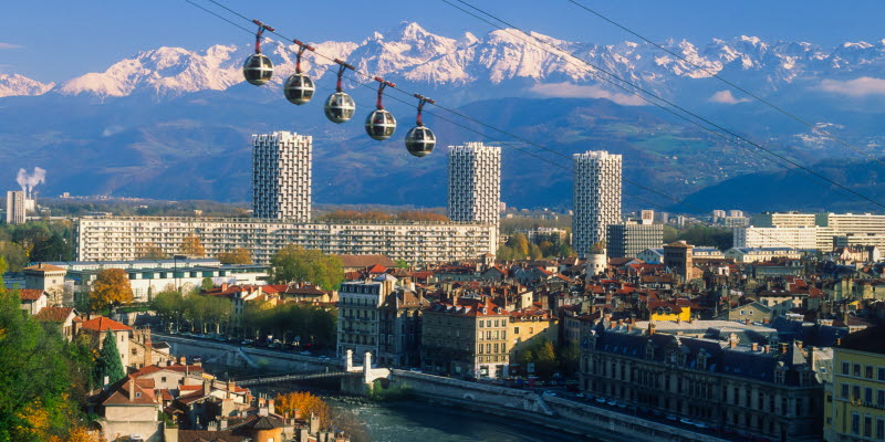 Grenoble med flod, linbana och alper i bakgrunden Grenoble med flod, linbana och alper i bakgrunden