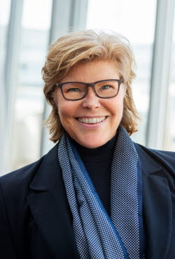 Ett foto av Katrin Bäckman, en blond kvinna med galsögon och blå scarf Ett foto av Katrin Bäckman, en blond kvinna med galsögon och blå scarf