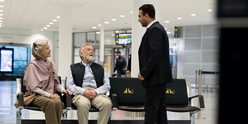 Ett äldre par sitter och en man står Ett äldre par sitter och en man står