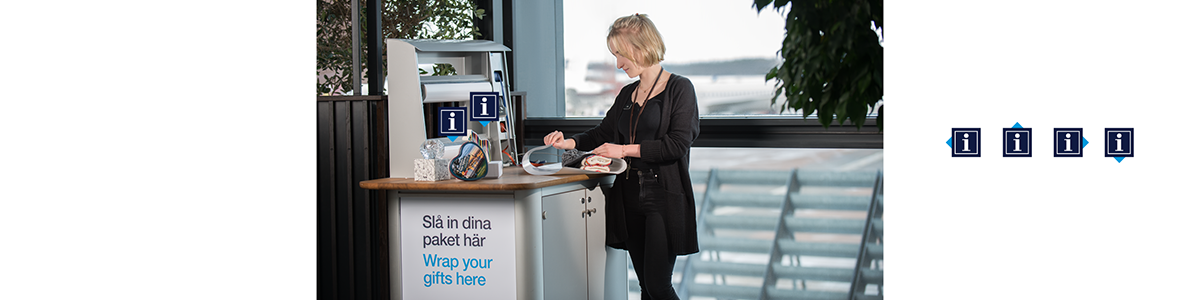 En kvinna slår in paket vid ett presentbord på Arlanda En kvinna slår in paket vid ett presentbord på Arlanda