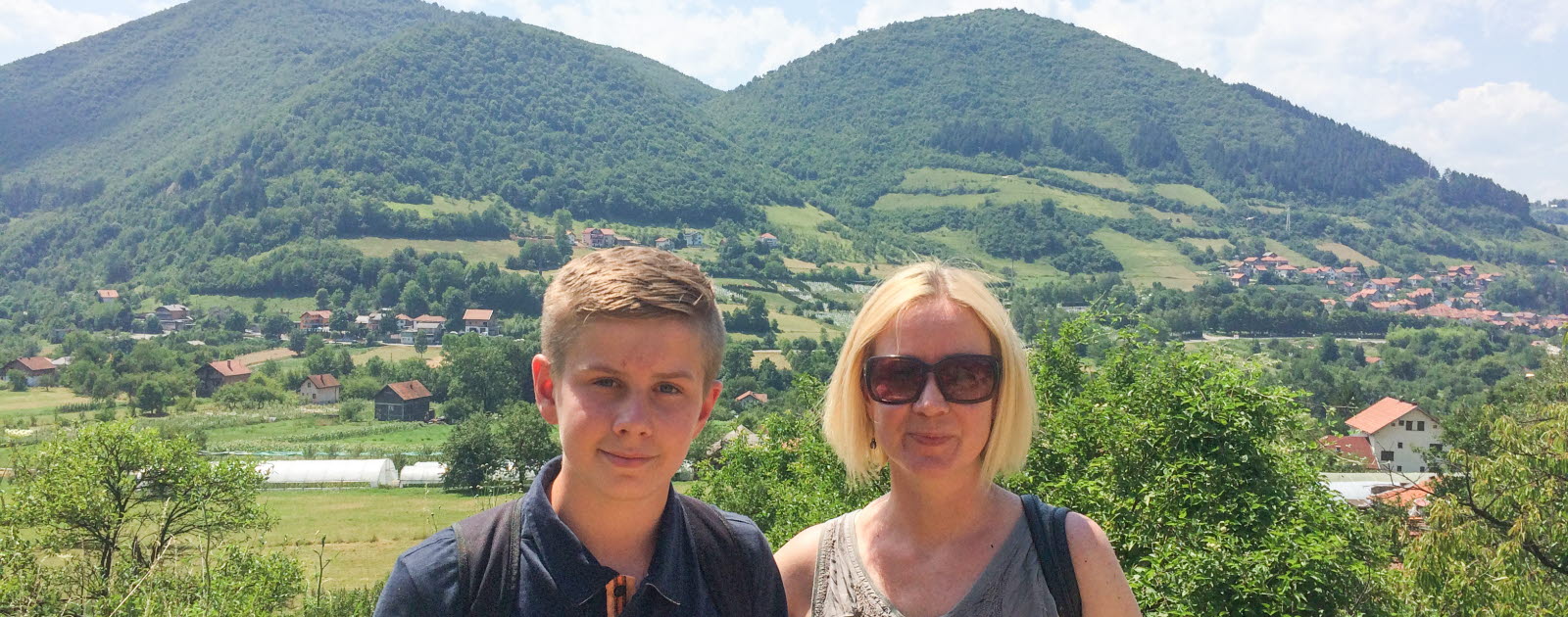 Pojke och kvinna framför grönklädda berg i Tuzla Pojke och kvinna framför grönklädda berg i Tuzla