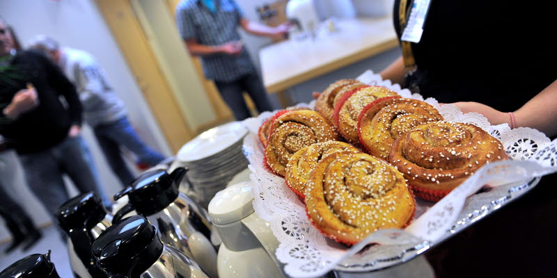 En person håller en bricka med bullar i ett konferensrum En person håller en bricka med bullar i ett konferensrum