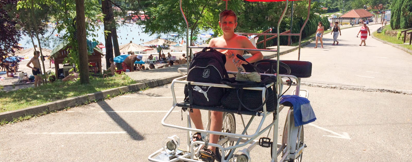 Pojke sitter i en cykel för två med rött tak Pojke sitter i en cykel för två med rött tak