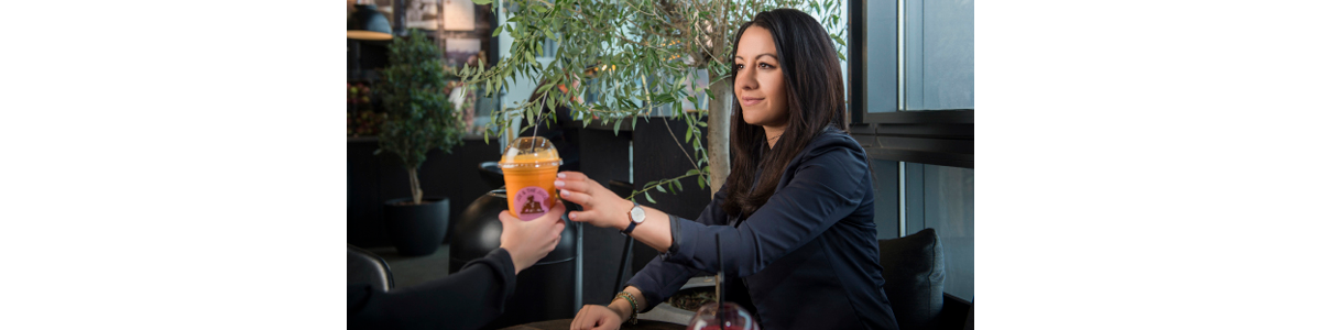 En kvinna tar emot en plastmugg med juice En kvinna tar emot en plastmugg med juice