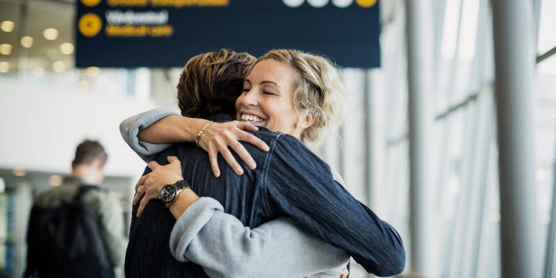 Kvinna kramar en resenär på flygplatsen Kvinna kramar en resenär på flygplatsen