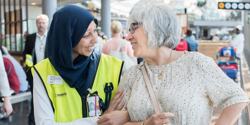 Flygplatsanställd pratar med resenär Flygplatsanställd pratar med resenär