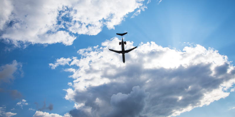 Flygplan i luften mot blå himmel och moln Flygplan i luften mot blå himmel och moln