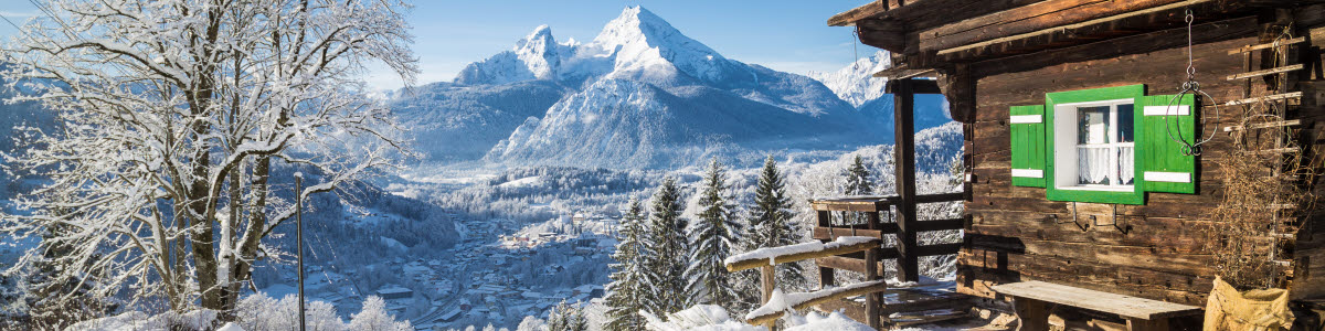 Panoramautsikt över det natursköna vita vinterlandskapet i Alperna med traditionella gamla trähytter på en vacker kall solig dag med blå himmel och moln Panoramautsikt över det natursköna vita vinterlandskapet i Alperna med traditionella gamla trähytter på en vacker kall solig dag med blå himmel och moln